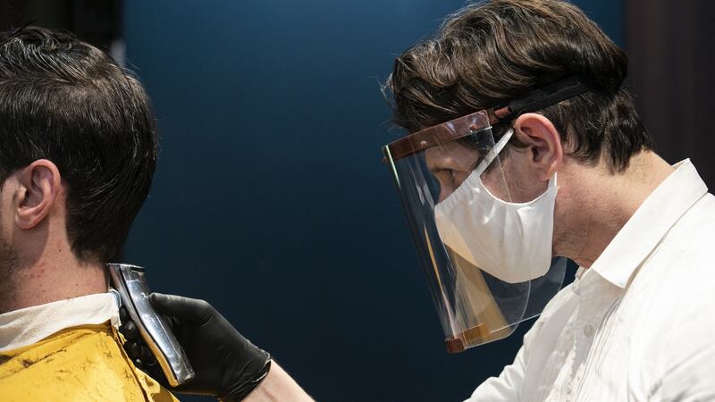 A barber gives a haircut in Athens wearing PPE. Photograph: Yorgos Karahalis/Bloomberg