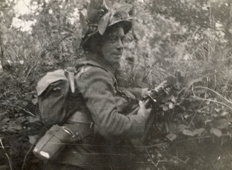 A camouflaged infantryman in an unidentified location, with Lee Enfield rifle and pickaxe. (Military Archives).