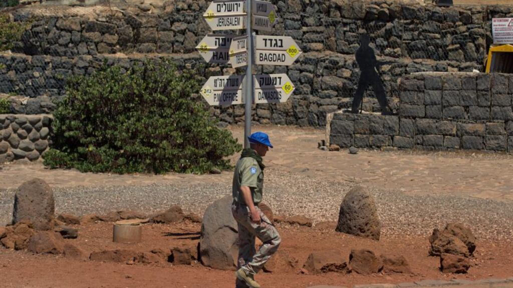An UN peacekeeper passes a road sign at the Bin Tal area in the Golan Heights near the Quneitra crossing, on the Israel-Syrian border yesterdau. The UN says it is working to secure the release of 43 peacekeepers. Photograph: Atef Safadi/EPA