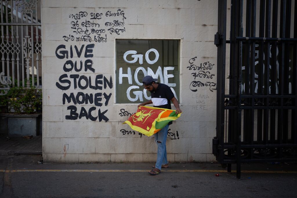 A protester unfurls the Sri Lankan national flag at the vandalised gateway of the presidential palace in Colombo on Wednesday. Photograph: Abhishek Chinnappa/Getty Images