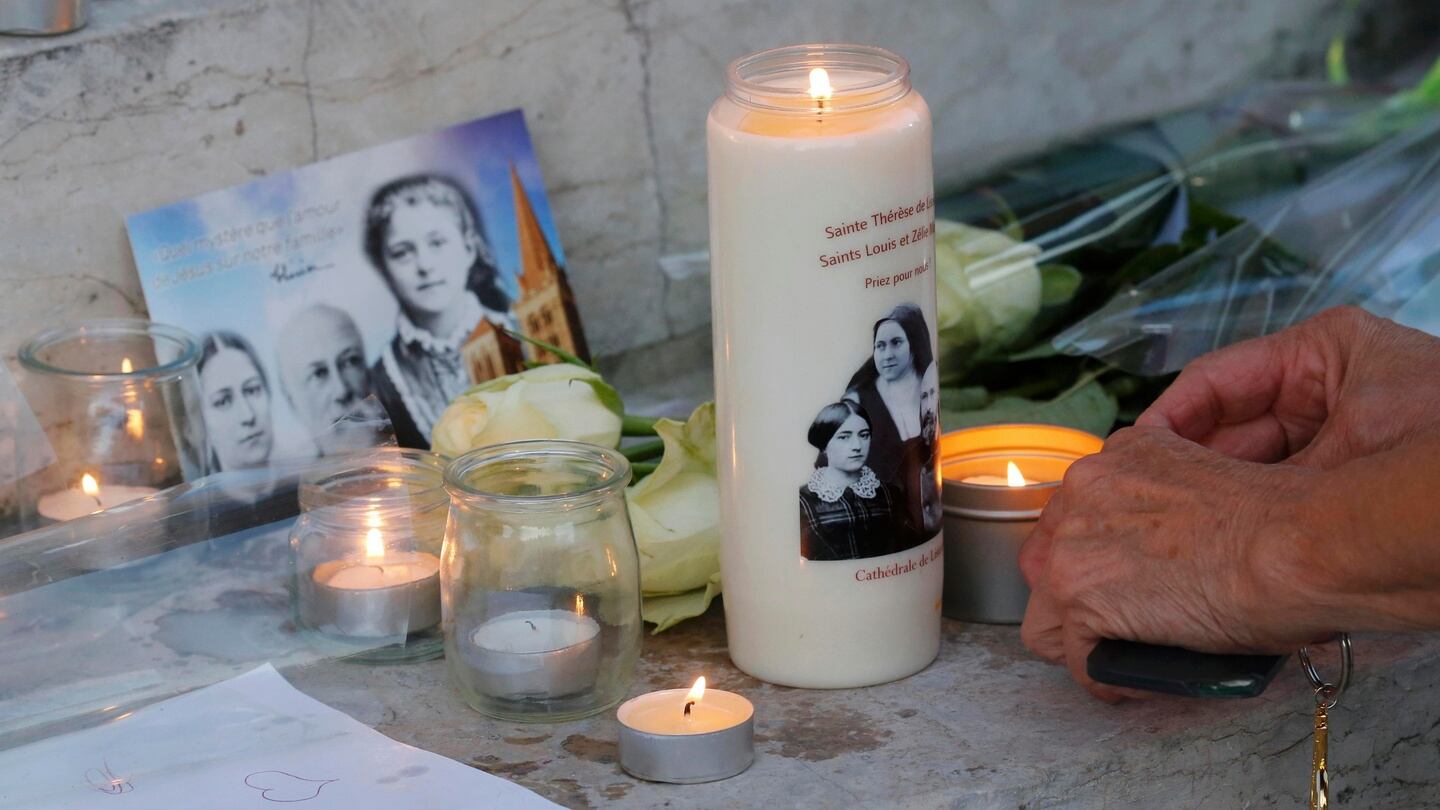 A woman places a candle with flowers and candles at the town hall in Saint-Étienne-du-Rouvray, near Rouen in Normandy, France, to pay tribute to French priest, Father Jacques Hamel, who was killed in an attack carried out by assailants linked to Islamic State. Photograph: Pascal Rossignol/Reuters