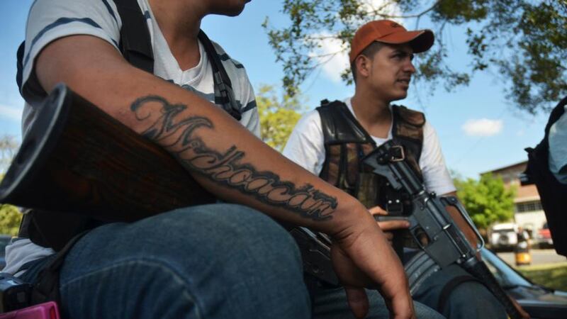 A vigilante sports a tattoo that reads ‘Michoacan’ while sitting with others on the outskirts of Paracuaro on January 10th. Photograph: Alan Ortega/Reuters