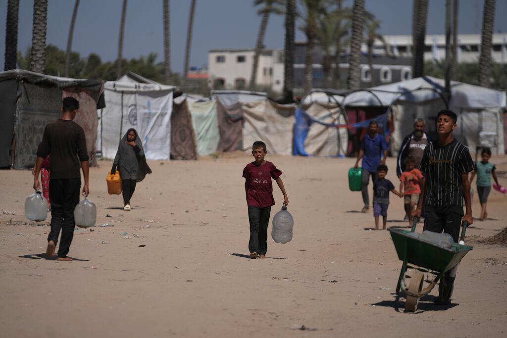 Palestinians carry containers for water at a camp for the displaced in Deir al-Balah, Gaza Strip. Photograph: Abdel Kareem Hana/AP