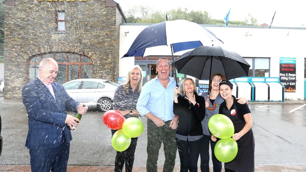 Martin Manley of the National Lottery pops champagne while Barry O’Sullivan (centre left) owner of the Centra Store and service station in Innishannon, Co Cork, where the winning ticket was bought  is pictured with staff including  Sylwia Ardron, Monika Twomey, Donna Madden and Renata Swiatek. Photograph: Mac Innes Photography