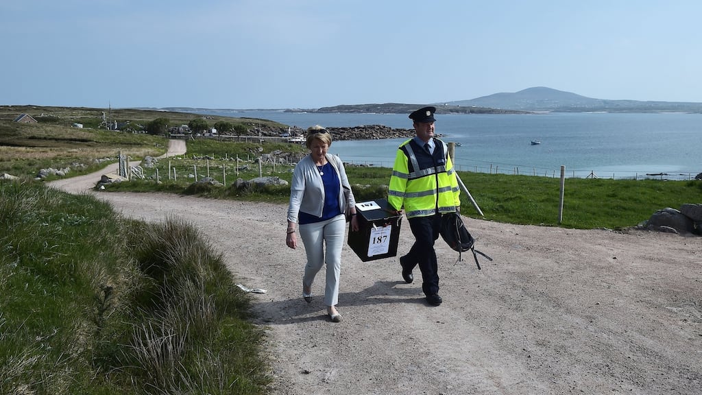 Garda Pat McElroy helps presiding officer Nancy Sharkey carry a ballot box as they walk to the local polling station in Gola Island, off Donegal, on Thursday. Photograph: Charles McQuillan/Getty Images