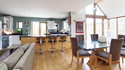 The open-plan living area has kitchen to the front, a seating area with a solid fuel stove, and space for a large dining table