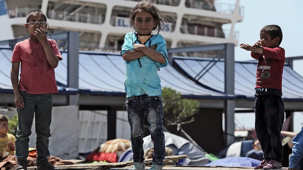 Children stand on top of a track at a makeshift refugee camp at the port of Piraeus.  EPA/SIMELA PANTZARTZI