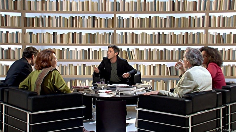 Caché: a television show positions the main character in front of a 2D wall of books to encourage us to recognise his television persona as a facade.