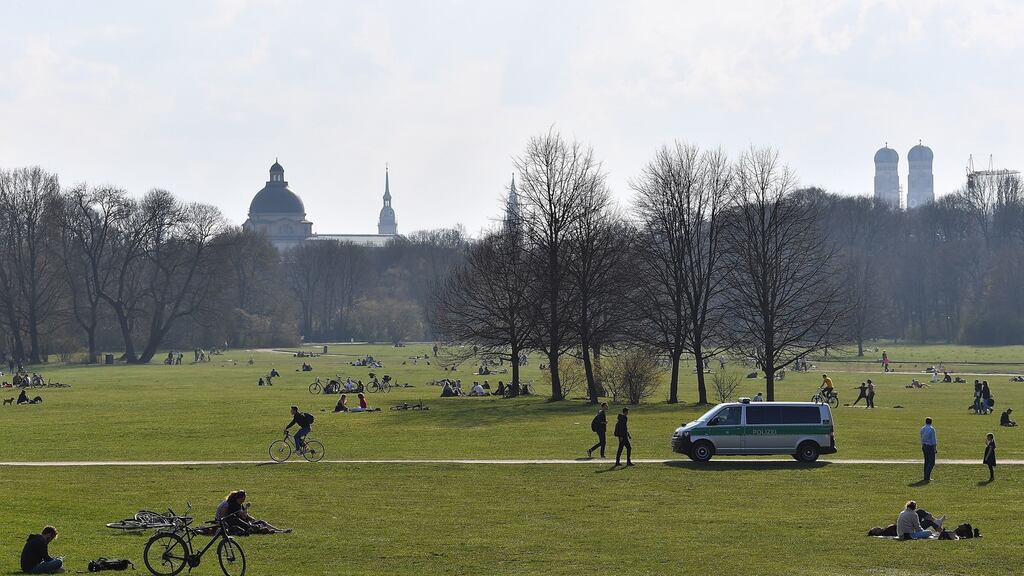 A police car patrols between crowds of people at the English Garden in Munich on Friday. Photograph: Lukas Barth-Tuttas/EPA