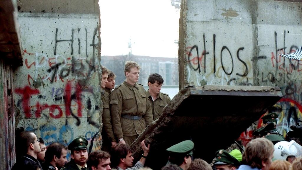 East German border guards look through a hole in the Berlin Wall after demonstrators pulled down the segment at the Brandenburg Gate in Berlin. Photograph: Lionel Cironneau/File/AP Photo