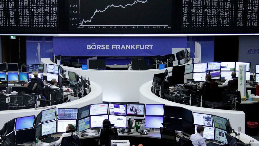 Traders are pictured at their desks in front of the DAX board at the stock exchange in Frankfurt, Germany, today.
