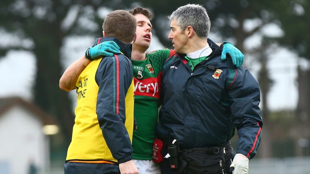 Lee Keegan is helped from the field by selector Tony McEntee and team doctor Seán Moffatt after a clash of heads with Cork’s Eoin Cadogan during Sunday’s football league clash. Photograph: James Crombie/Inpho