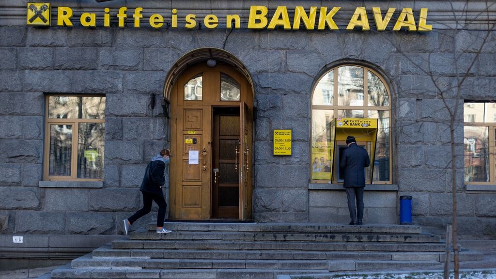A pedestrian enters a Raiffeisen Bank JSC branch in Kyiv, Ukraine, on Tuesday. Photograph: Ethan Swope/Bloomberg