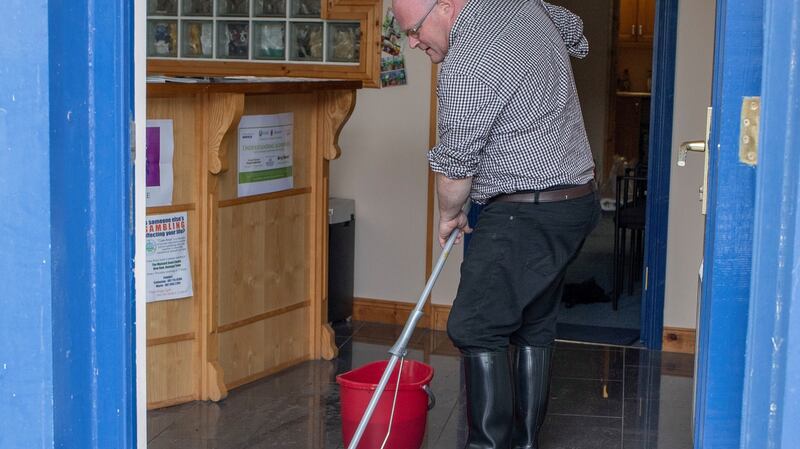 Sean Bonner clearing out flood water from the Alzhemiers Society charity shop in Donegal Town. Photograph: North West Newspix