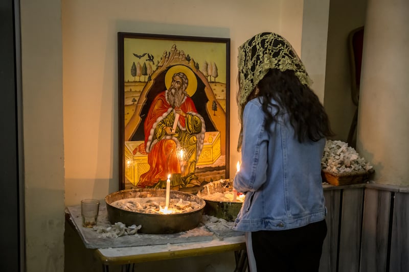 A woman stands in front of candles in the basement of the Mar Elias Greek Orthodox church in Dweil'a, Damascus