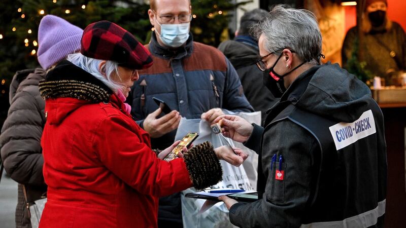 A ‘Covid-check’ inspector checks digital vaccination certificates on visitors’ smartphones at a Christmas market in Cologne, Germany on Monday. Photograph: Sascha Steinbach/EPA