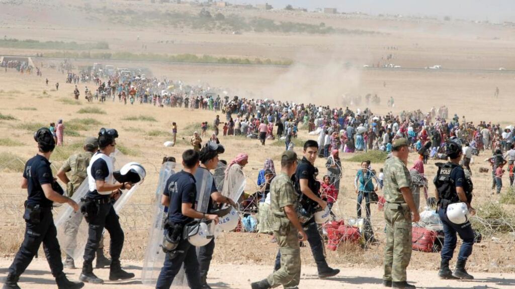 Turkish police and soldiers observe Syrian Kurds waiting   to cross into Turkey near the southeastern town of Suruc in Sanliurfa province yesterday. Photograph: Reuters