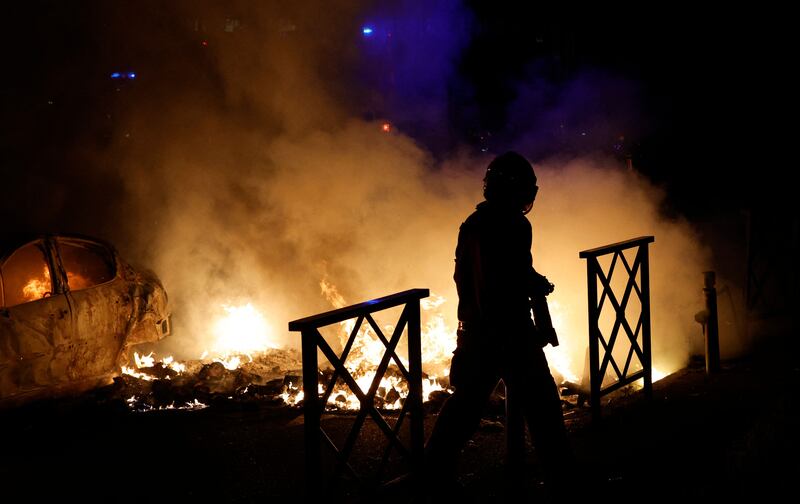 A firefighter extinguishes the flames of a car set on fire during protests in Nanterre. Photograph: Geoffroy Van Der Hasselt/Getty
