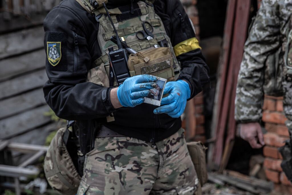A Ukrainian soldier gathers personal items from the body of a Russian soldier in the city of Kupiansk-Vuzlovyi near the frontline in Ukraine’s northeastern Kharkiv region on November 1st, 2022. Photograph: Finbarr O'Reilly/The New York Times