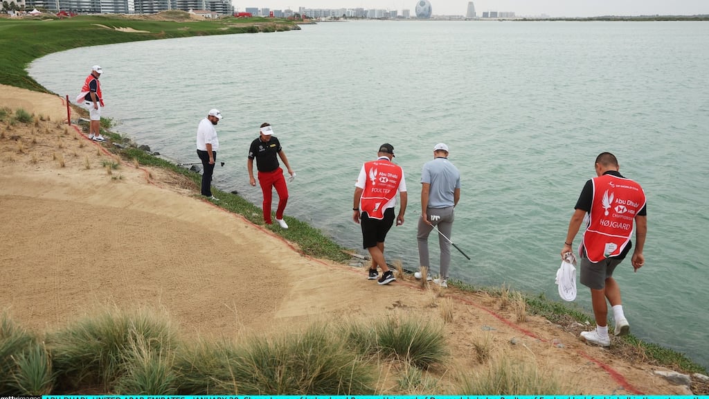Shane Lowry and Rasmus Hojgaard of help Ian Poulter look for his ball in the water on the 16th hole during the first round of the Abu Dhabi HSBC Championship at Yas Links Golf Course. Photograph: Andrew Redington/Getty Images