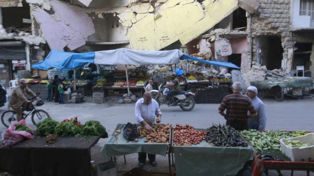 Civilians shop for vegetables and fruits displayed in front of a damaged building in Aleppo’s Bustan al-Qasr neighborhood, Syria. Photograph: REUTERS/Hosam Katan