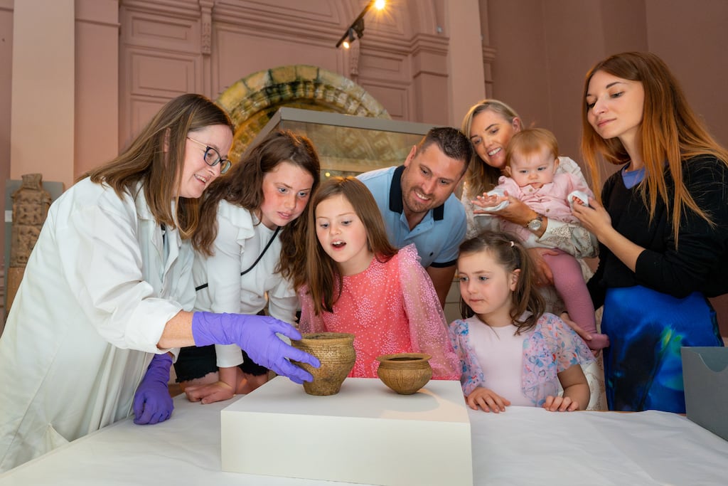 Nigel Meredith, his wife Alma, their daughters, Lexis (11), Andrea (eight), Charlotte (four), one-year-old Baya and au pair Amanda Rodriguez examine the Bronze Age artefacts they found, with National Museum collections assistant Joanne Gaffrey. Photograph: Conor Mulhern/Eyeon