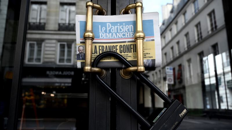 ‘France confined’ reads the headline on the Parisien daily newspaper on the locked gate of a closed cafe in Paris. Photograph: Philippe Lopez/AFP