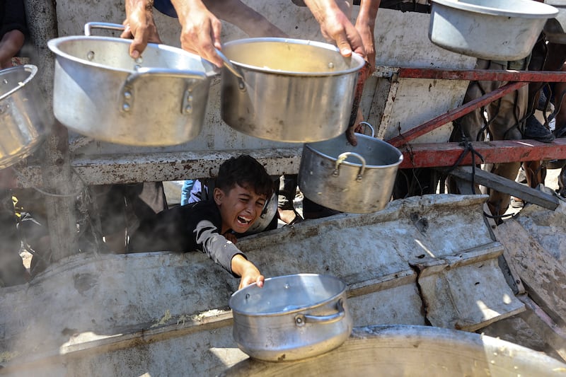 A Palestinian boy extends an empty pot in front of a charity kitchen to receive cooked rice in Gaza City on Saturday. Photograph: Omar Al-Qattaa/Getty