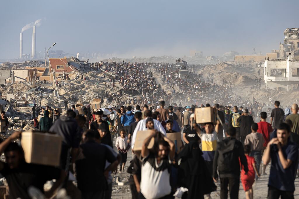 Palestinians carry parcels of donated food at an aid distribution point northwest of Gaza City. Photograph: Saher Alghorra/The New York Times