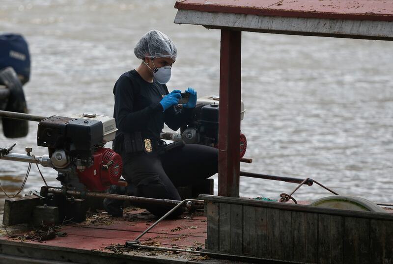 A federal police officer takes pictures of a seized boat during the search for British journalist Dom Phillips and Indigenous affairs expert Bruno Araujo Pereira