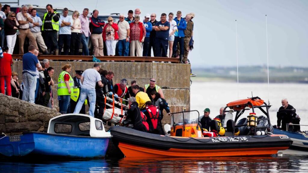 The bodies of two fishermen being recovered at Seafield Pier, Quilty last year.