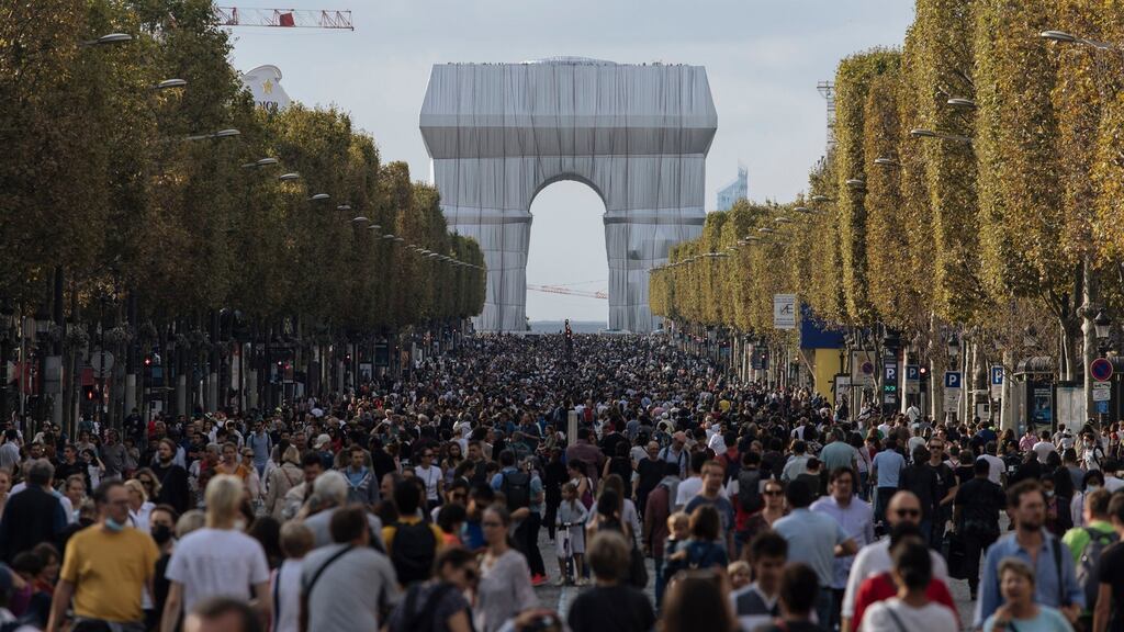 People walk along the Champs Elysees Avenue, Paris, during the "day without cars", with the Arc de Triomphe in the background, Sunday, Sept. 19, 2021. It is the sixth year the city has held a car free day in an attempt to reduce traffic and ease air pollution. (AP Photo/Lewis Joly)