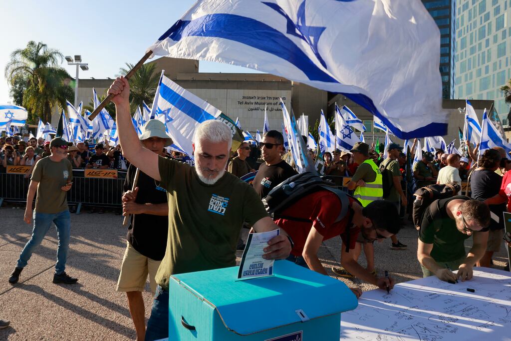An Israeli military reservist waves a national flag in Tel Aviv on July 19th as he drops a signed declaration in a box, announcing the suspension of his voluntary reserve duty in a protest against the government's judicial overhaul bill. Photograph: Menahem Kahana/AFP via Getty Images