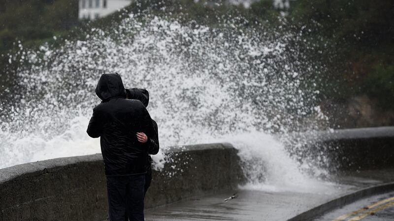 A wave breaks over a wall as bystanders look out across the Irish Sea during Storm Brian in Dublin, Ireland on Saturday. Photograph: Clodagh Kilcoyne/Reuters