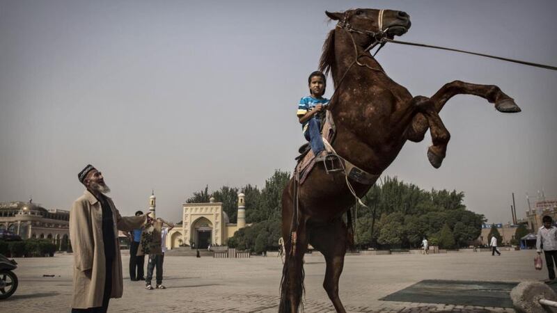 A Uighur boy sits atop a horse as he has his picture taken outside the Id Kah Mosque before the Eid holiday on July 28th, in old Kashgar, Xinjiang province, China. Photograph: Kevin Frayer/Getty Images