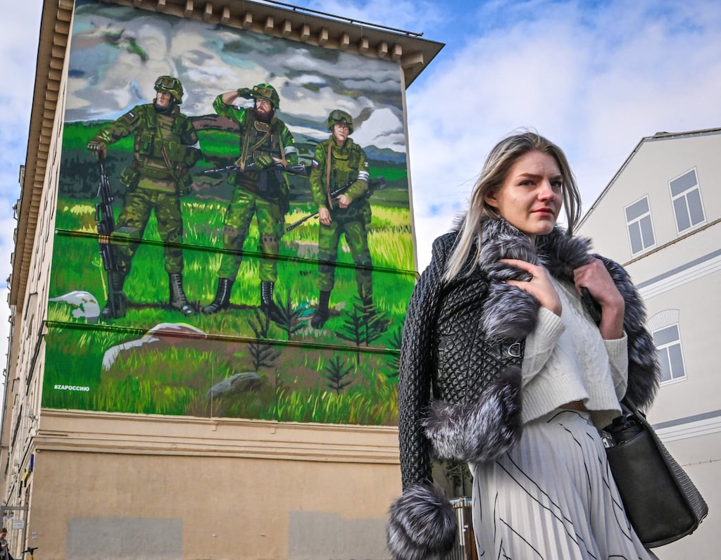 A woman walks past a building in central Moscow with graffiti depicting Russian servicemen with the 'Z' symbol on their uniform. Many men have left the capital to avoid being called up to fight in the war in Ukraine. Photograph: Yuri Kadobnov/Getty Images