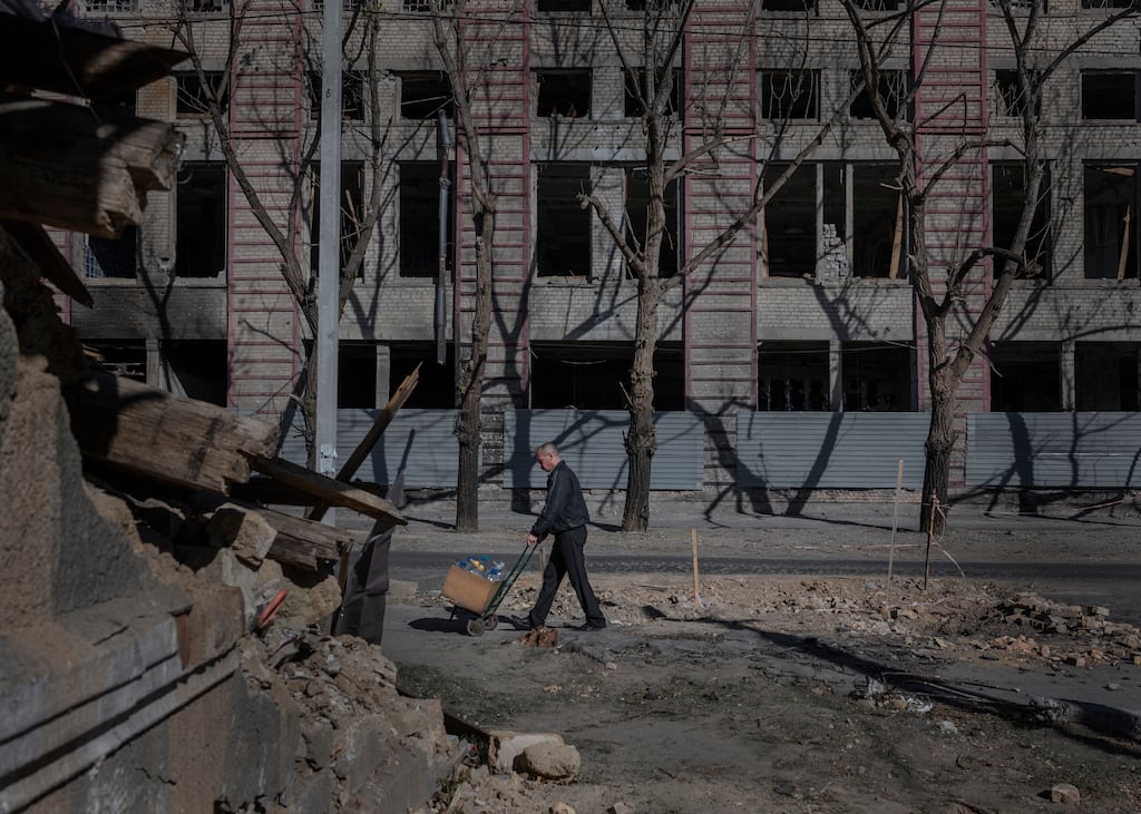 A hand cart is wheeled past a bomb crater in the road in Kherson on October 28th. Photograph: Emile Ducke/The New York Times
