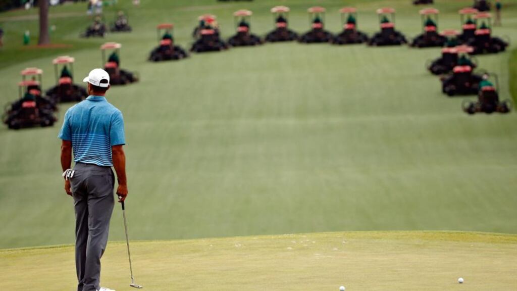 Tiger Woods stands on the green as greenkeepers mow the fairways during a practice round prior to the start of the 2015 Masters Tournament at Augusta National Golf Club. Photograph: Ezra Shaw/Getty Images