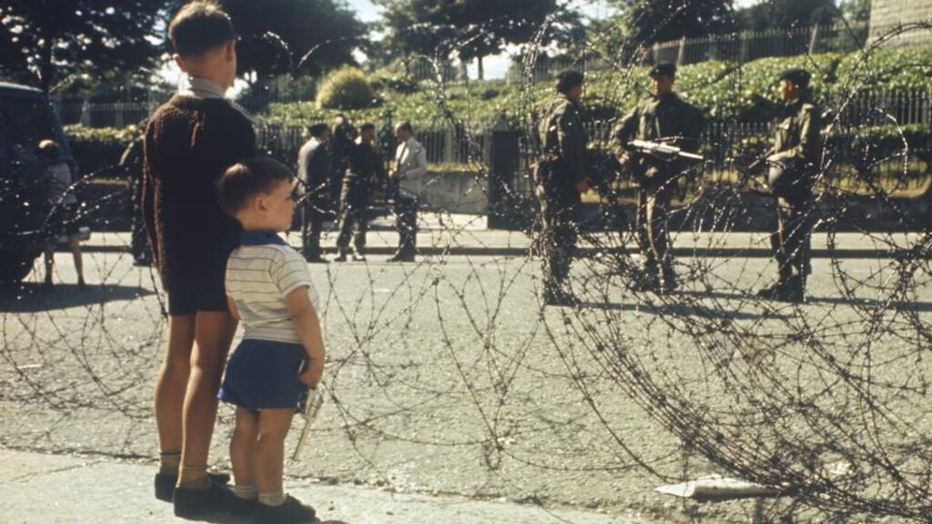 Troubles children: two little boys look through barbed wire at British soldiers on the Crumlin Road in Belfast. Photograph: Rolls Press/Popperfoto/Getty Images