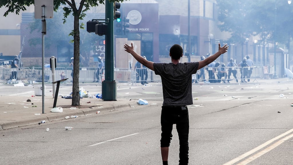 A protester raises his arms as tear gas floats outside the Minneapolis police 3rd Precinct during a second day of demonstrations. Photograph: EPA