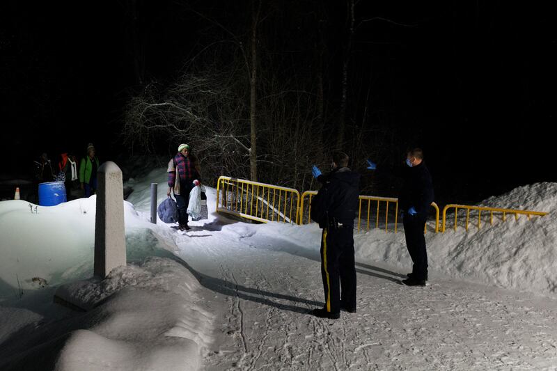 Migrants arriving at the Roxham Road border crossing from New York City listen as Canadian police officers explain that they'll be arrested upon setting foot in Canada, in Saint-Bernard-de-Lacolle. Photograph: Nasuna Stuart-Ulin/New York Times