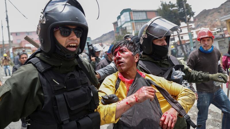 Members of Bolivia’s security forces detain a man injured during clashes between supporters of Evo Morales and opposition supporters in La Paz on Monday. Photograph: Carlos Garcia Rawlins/Reuters