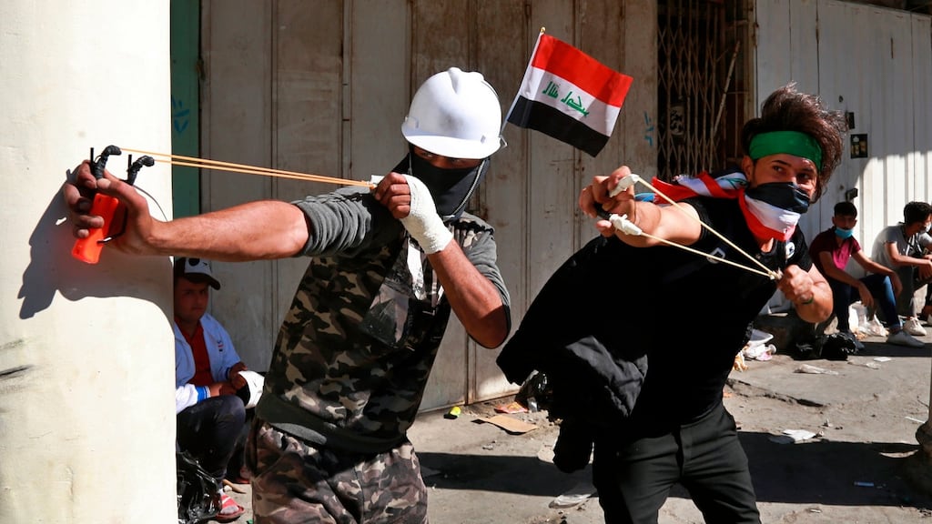 Anti-government protesters throw stones at security forces during clashes in the al-Rasheed street in Baghdad on Friday. Photograph: Khalid Mohammed/AP