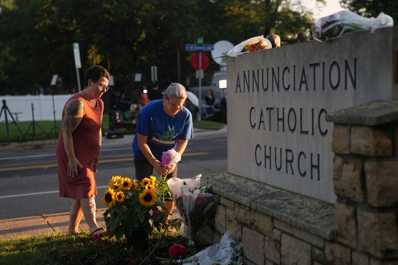 Susan Saly (right) and Meagan Pierlouissi place flowers at a memorial at Annunciation Catholic Church after Wednesday’s school shooting in Minneapolis. Photograph: Abbie Parr/AP