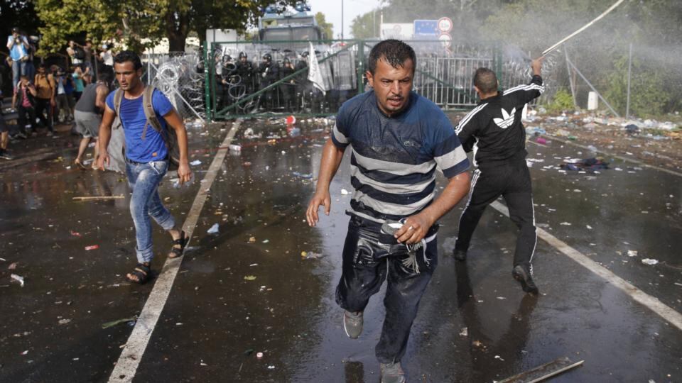 Migrants run as Hungarian riot police fire tear gas and water cannon at the border crossing with Serbia in Roszke,  September 16th, 2015. Photograph: Marko Djurica/Reuters