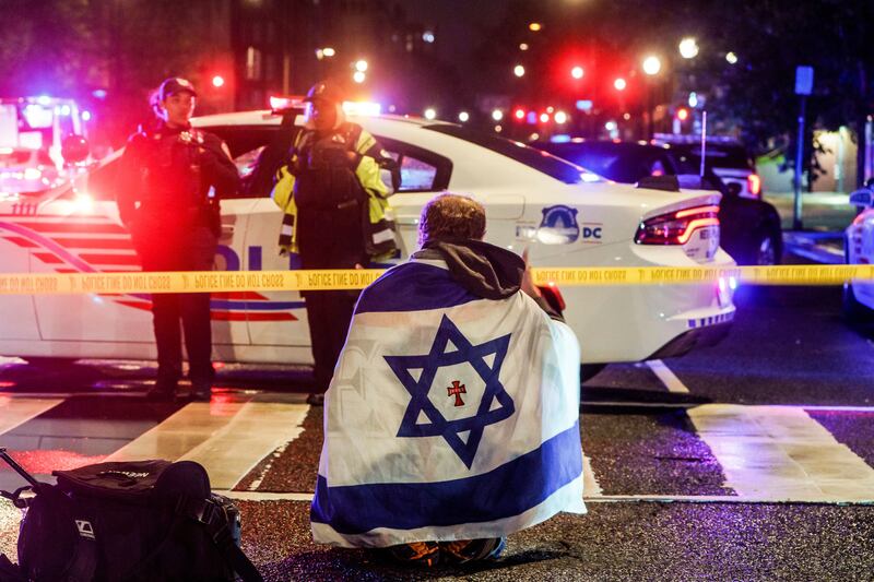A man with an Israeli flag draped on his shoulders near the scene where Sarah Lynn Milgrim and Yaron Lischinsky were shot and killed in Washington on Wednesday night. Photograph: Will Oliver/EPA
