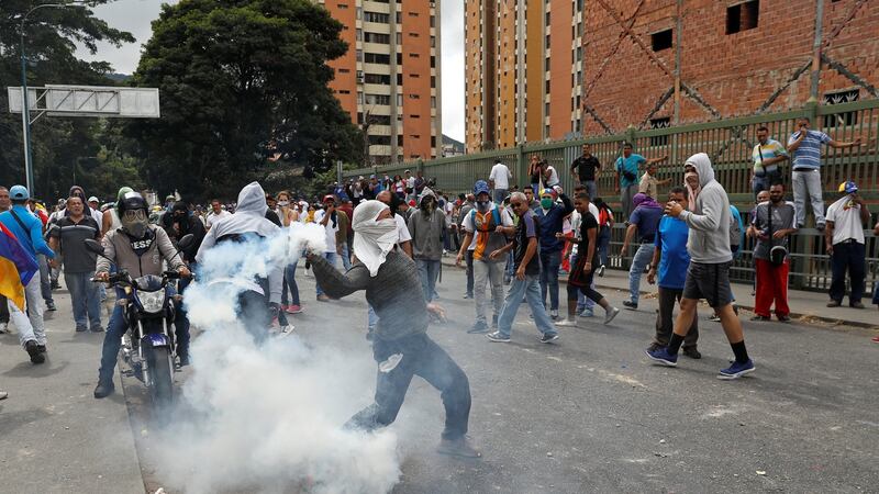 A demonstrator throws back a tear gas canister in Caracas. Photograph: Reuters