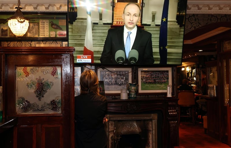 A member of staff watches as Taoiseach Micheál Martin gives his address to the nation announcing the end to Covid-19 restrictions in McGrattans bar close to Government Buldings on Fitzwilliam Lane on Friday. Photograph: Laura Hutton/The Irish Times