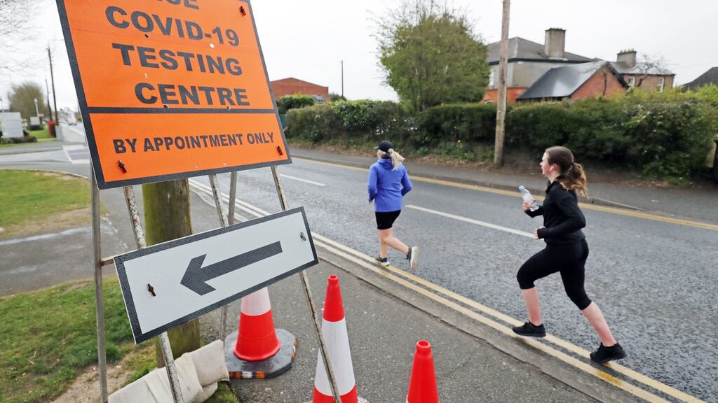 Joggers pass a sign for a testing centre in Newbridge in Co Kildare. Photograph: PA