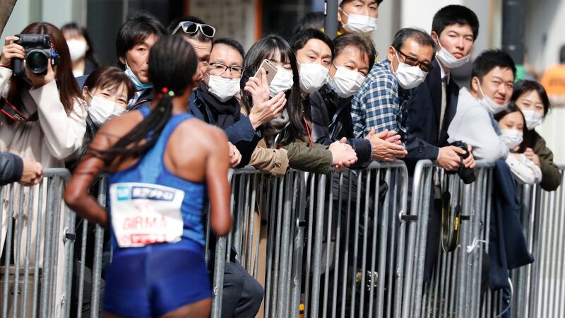 Spectators wearing masks watch a runner at the Tokyo Marathon in Tokyo, Sunday. Organisers of the Tokyo Marathon reduced the number of participants out of fear of the spread of the coronavirus from China. The general public was essentially barred from the race. Photograph: Shuji Kajiyama/AP